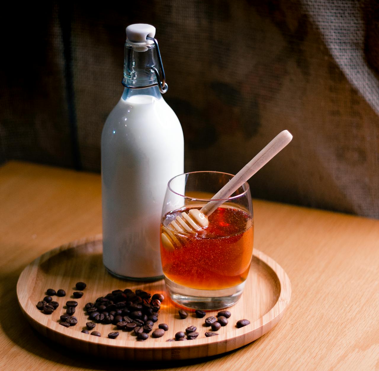 home-img Elegant setup featuring a milk bottle and honey glass on a wooden tray with coffee beans.